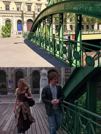 一个人和一个女人站在城市中的一座绿色桥上 前面是一座建筑物。