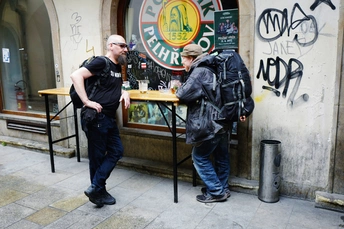 一些男人走在酒吧旁边的人行道上 一个人站在酒吧前面。