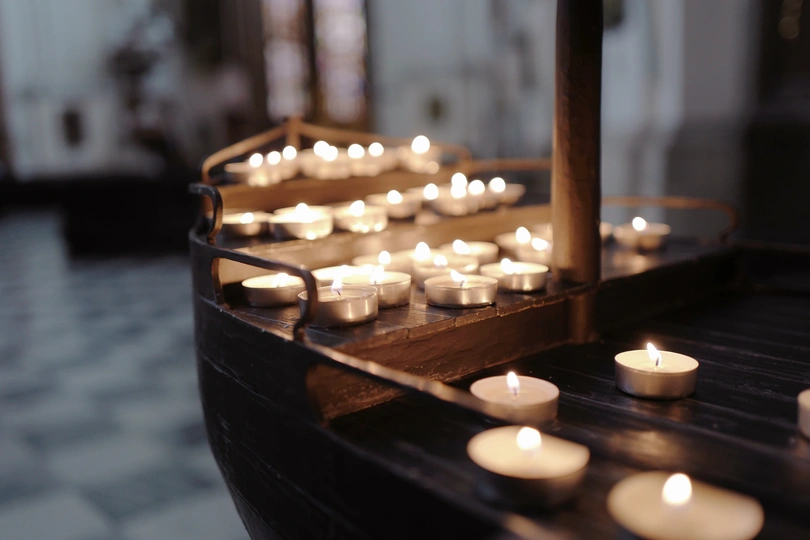 一艘木船漂浮在一座教堂里 周围有许多点亮的蜡烛和十字架。