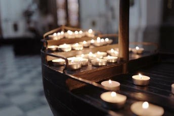 一艘木船漂浮在一座教堂里 周围有许多点亮的蜡烛和十字架。