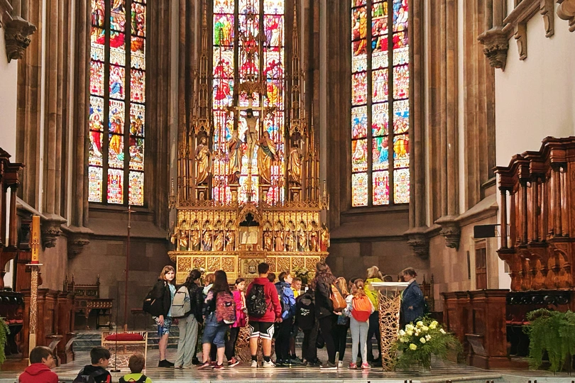 游客站在一座大教堂的圣坛前 有彩色玻璃窗