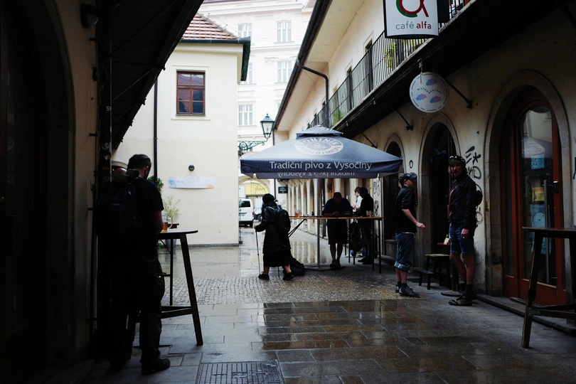 人们走在一条狭窄的街道上 桌子上放着伞。