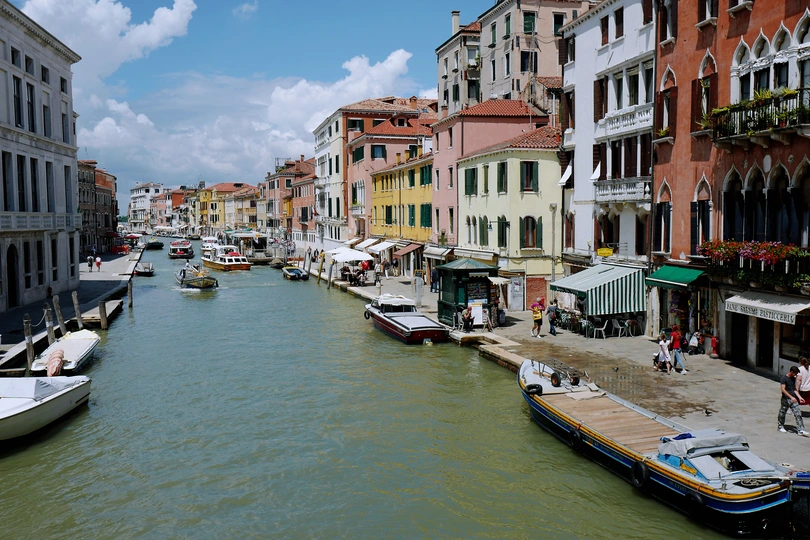 一个小运河 里面停满了许多船 旁边有几座建筑。