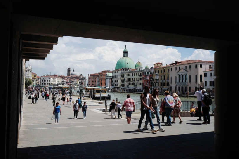 河边的广场上有一群人正在行走 周围有许多建筑物。