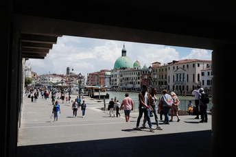 河边的广场上有一群人正在行走 周围有许多建筑物。