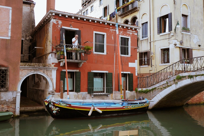 一条小船在一条运河旁边 旁边有建筑物。