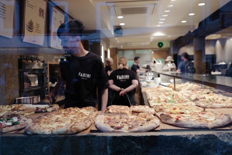 站在柜台后面有几个披萨的一个人