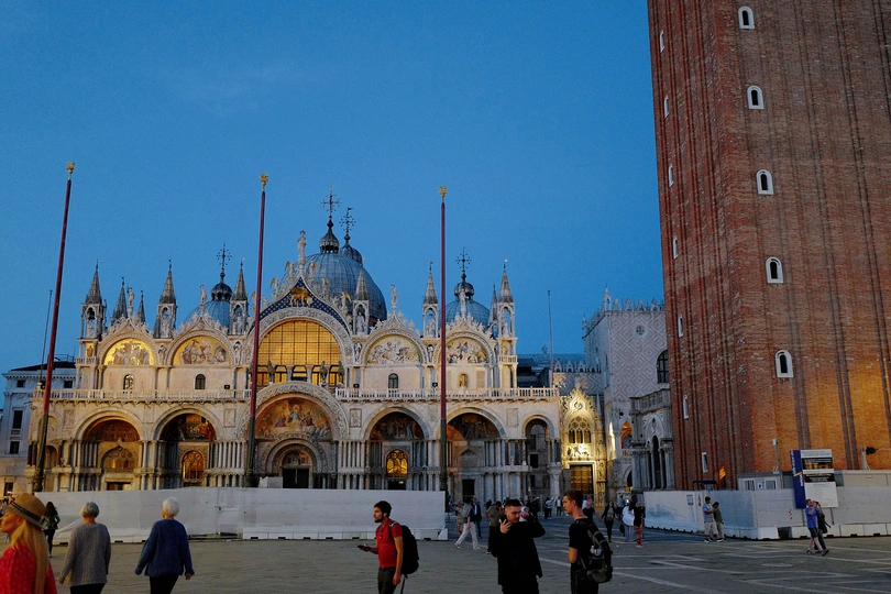 城市上空高耸的大钟楼 周围有人们走动。