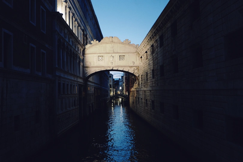 一条狭窄的运河 有黑暗的建筑物和一艘小船在水中。