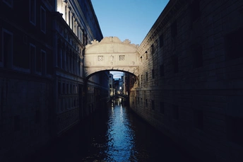 一条狭窄的运河 有黑暗的建筑物和一艘小船在水中。