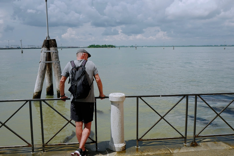 一个人背着背包站在码头上 眺望着海洋。
