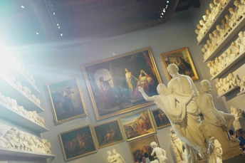 一个房间 墙上挂满了画作和图片 中央摆放着一座雕像和花瓶。