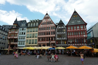 一个有许多人、五颜六色房子和遮阳伞的广场。