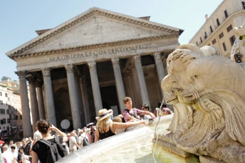 前方有一个人工喷泉 前方有一座狮子雕像 前方有一座大型建筑 前方有一群人。