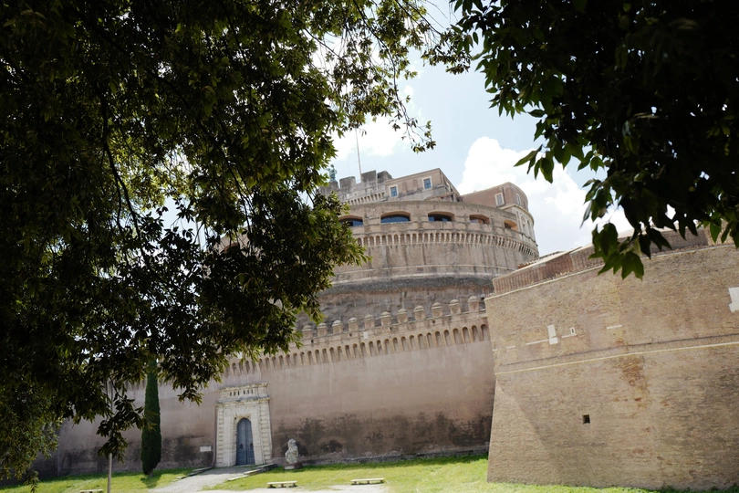 公园里的一棵大树下 人们坐在长凳上 城堡在背景中。