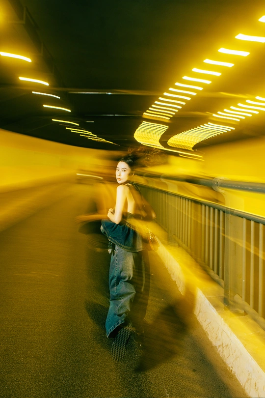 一个年轻人在隧道里骑滑板 一个年轻女孩在桥上走过去。