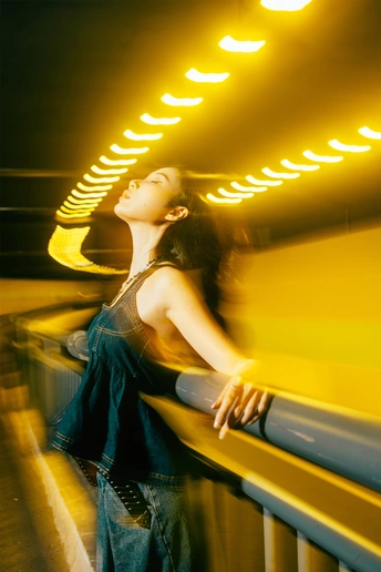 站在夜晚黄色灯光下的隧道中的年轻女子
