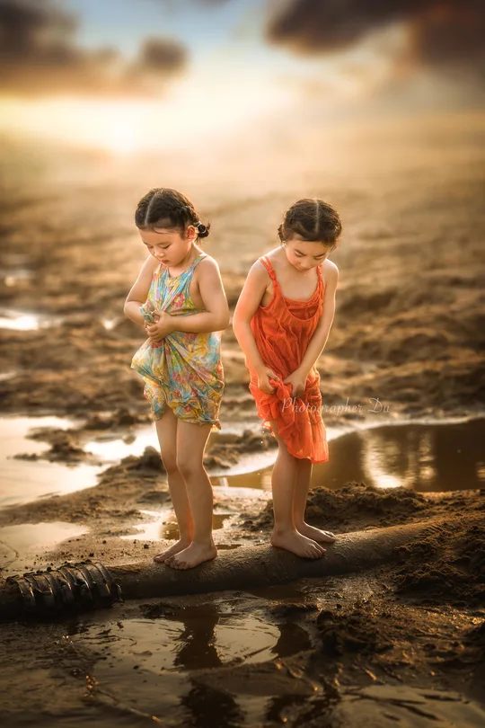 一个年轻男孩和一个小女孩在沙滩上玩耍 沙和水。