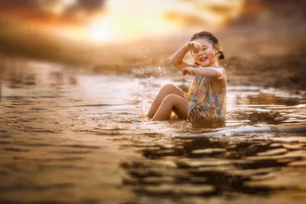 一个小女孩坐在湖或河的水里玩