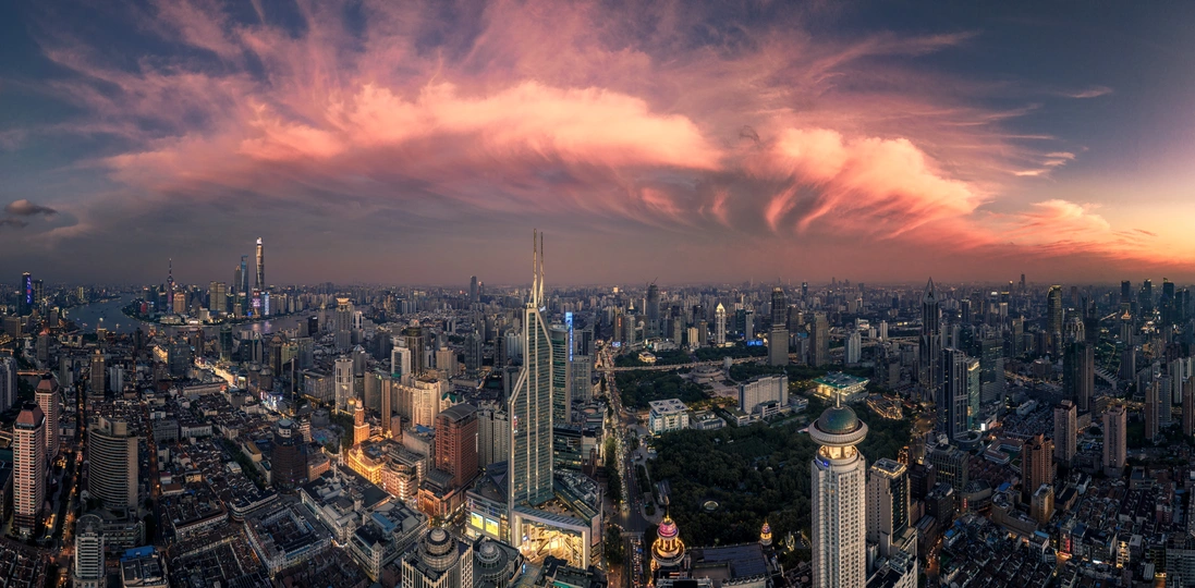 夕阳下的城市景观 高耸的建筑物和摩天大楼 天空中有一大朵云。