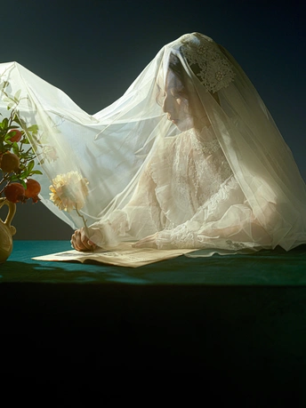 一位穿着白色婚纱的女人坐在一个放满花的桌子旁