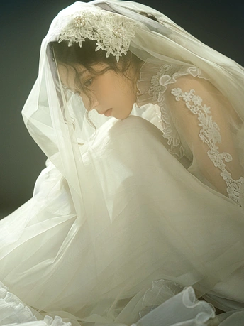 一个穿着白色婚纱和头纱的年轻女孩躺在床上