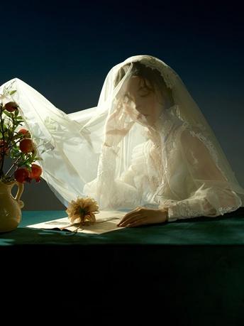 一位穿着白色婚纱的女人坐在一个放满花的桌子旁