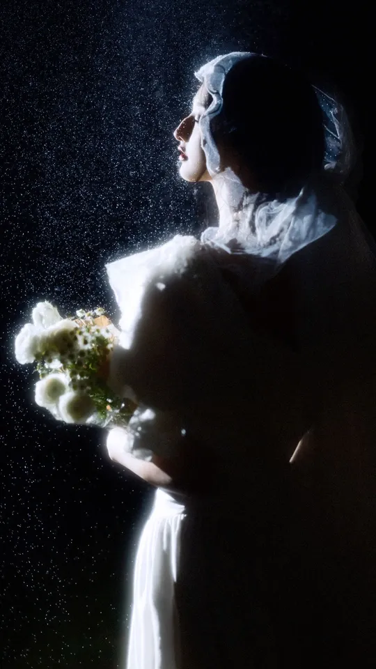 一位女子在雨中拿着一束白花