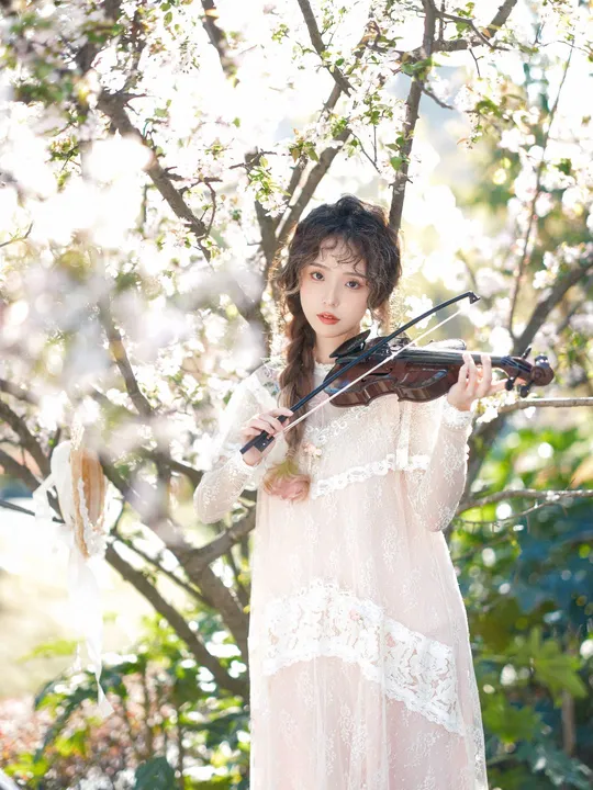 一位穿着白色连衣裙的年轻女子正在拉小提琴