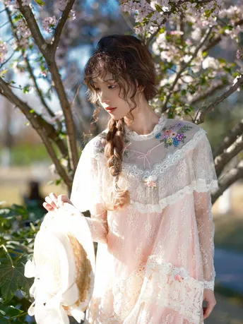 一位穿着白色连衣裙的美女站在一朵盛开的树下