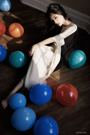 一位身着白色连衣裙被蓝色球环绕的年轻女子