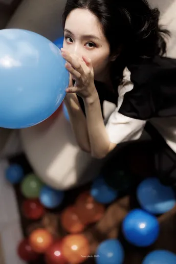 一位年轻女子举着蓝色的球靠近她的脸