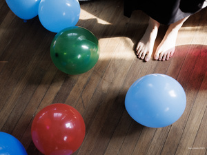一个人坐在木地板上 脚周围有气球。