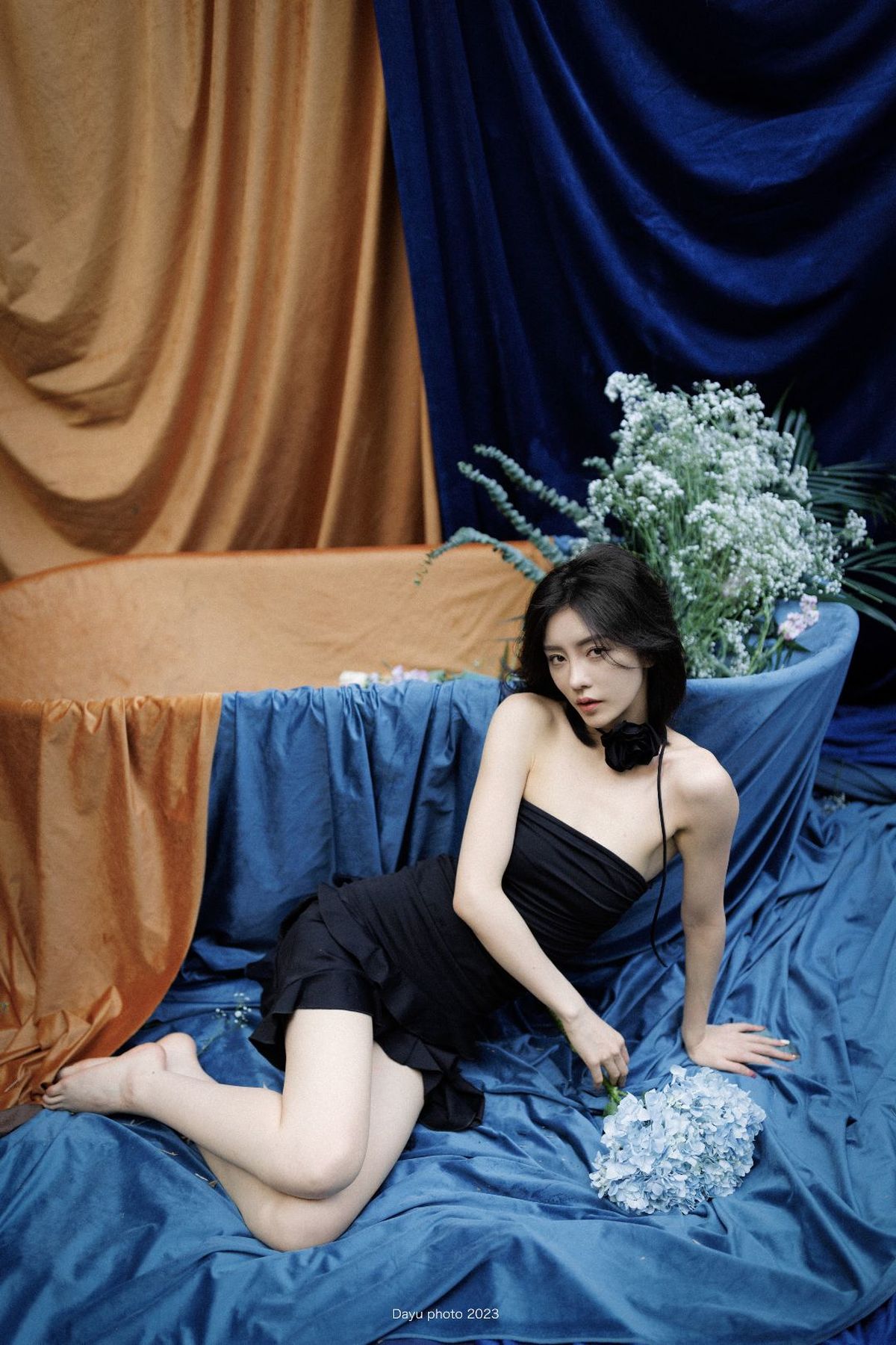 一个穿着黑色连衣裙的年轻女子坐在蓝色沙发上