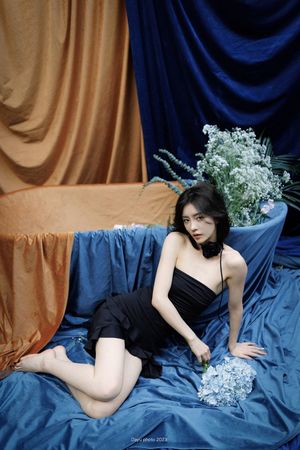 一个穿着黑色连衣裙的年轻女子坐在蓝色沙发上