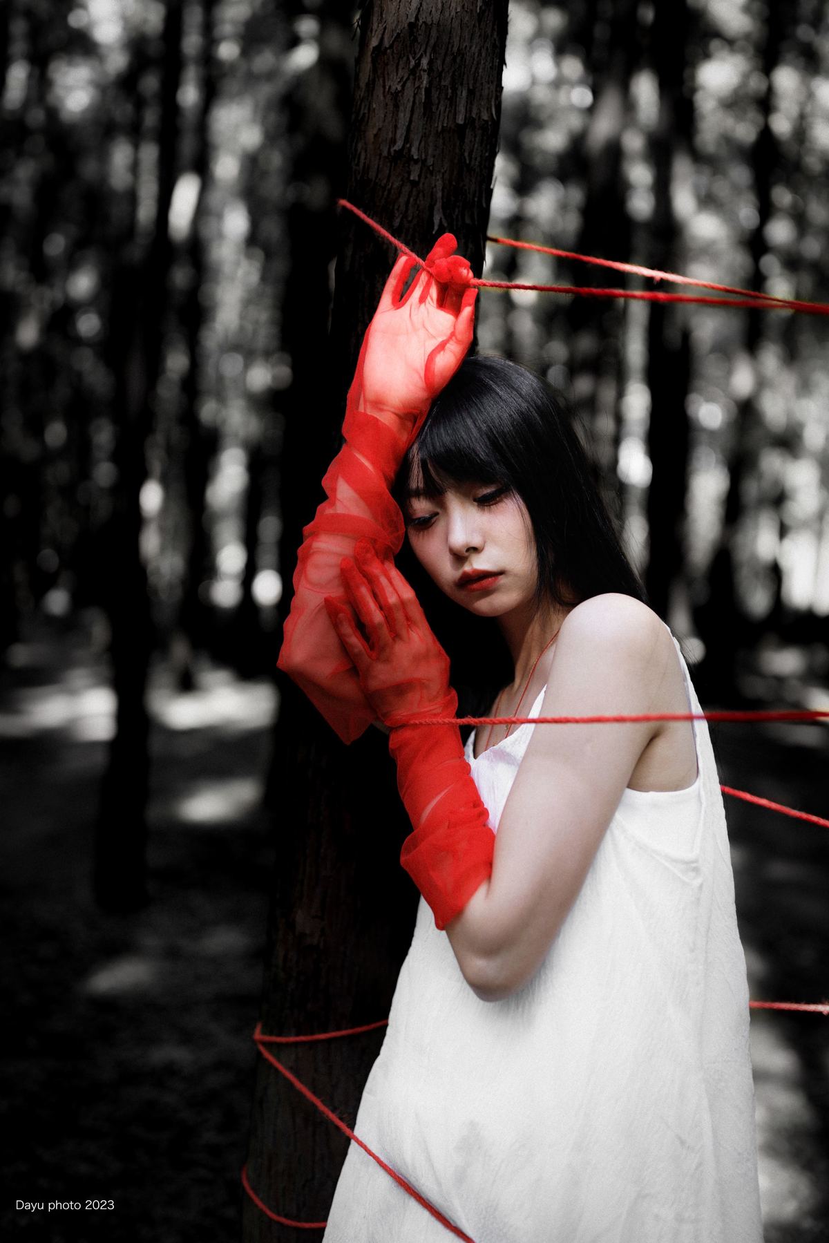 一个穿着白色连衣裙和红手套的女人手里拿着一只龙虾站在森林里