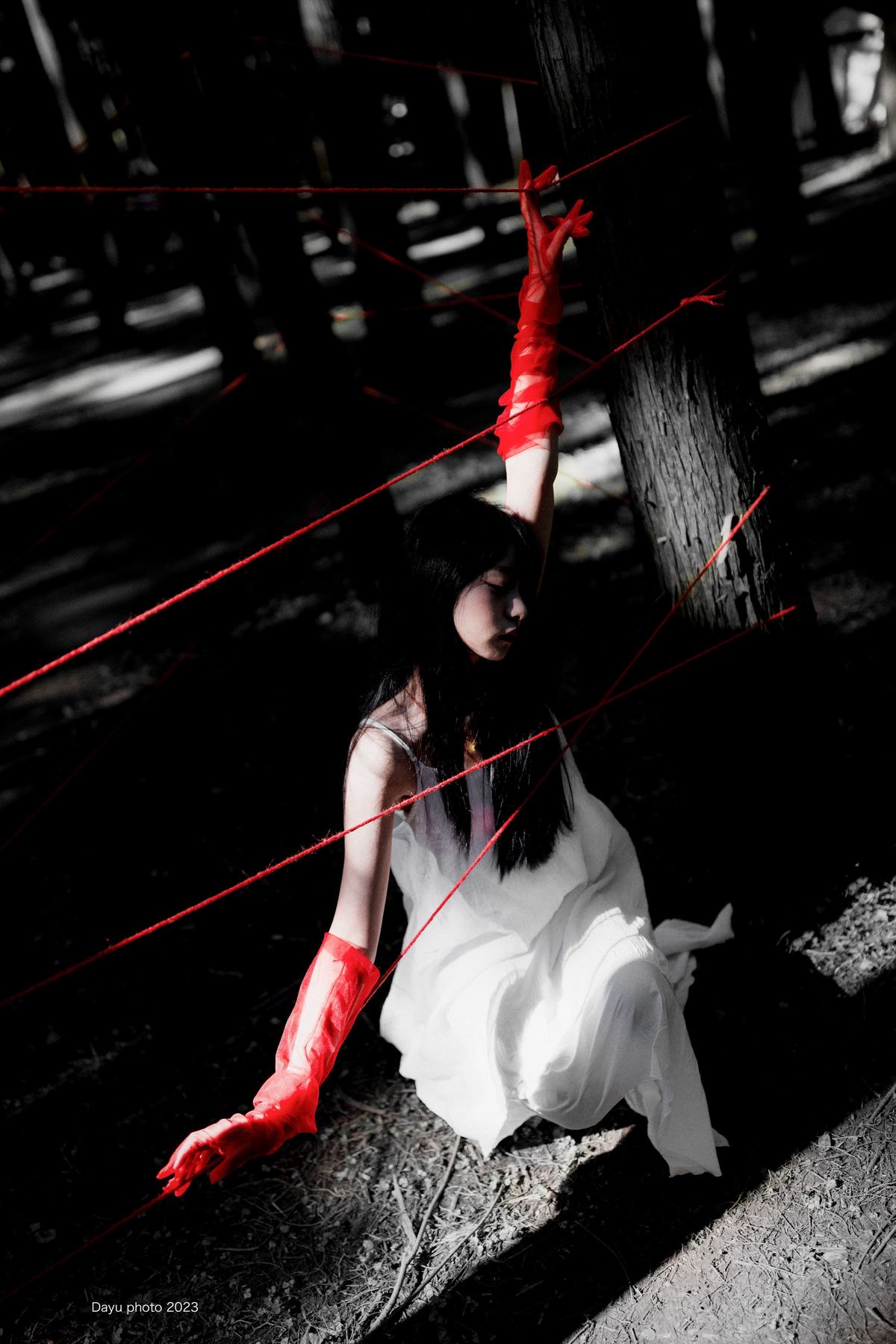 一个穿白色连衣裙和红色靴子 带着红色雨伞在森林里的女孩