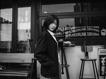 站在一个有吧台和窗边的椅子的小酒馆里的年轻女子