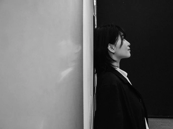 一位年轻女子靠在墙上看着冰箱