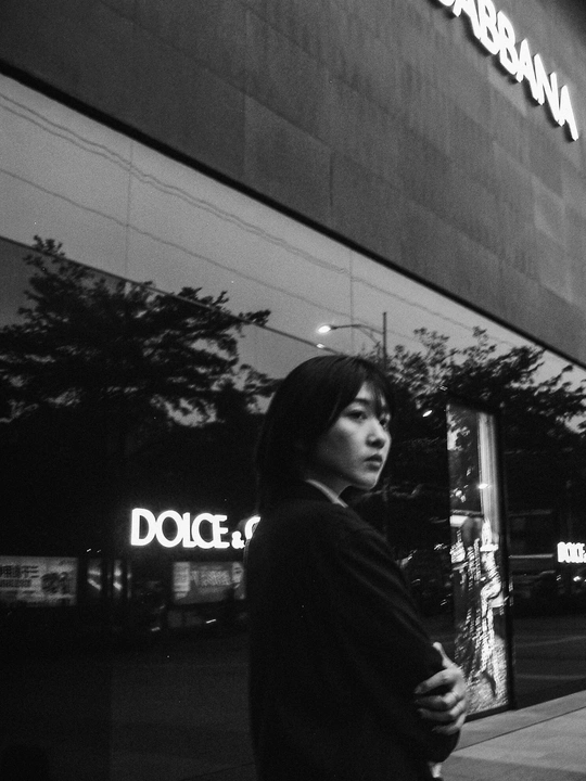 一张黑白照片 一对男女在夜晚走在人行道上 前方有一栋建筑。