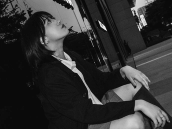 一张黑白照片 一位年轻女子坐在长凳上抽烟。