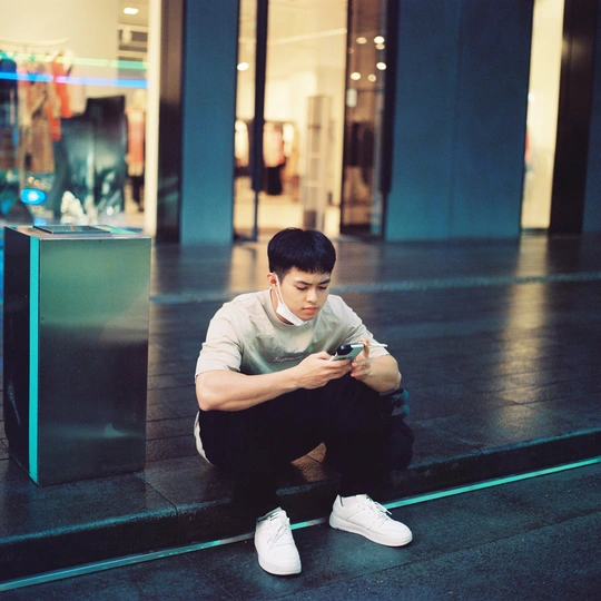 一个年轻人坐在商店地板上 正在看手机。