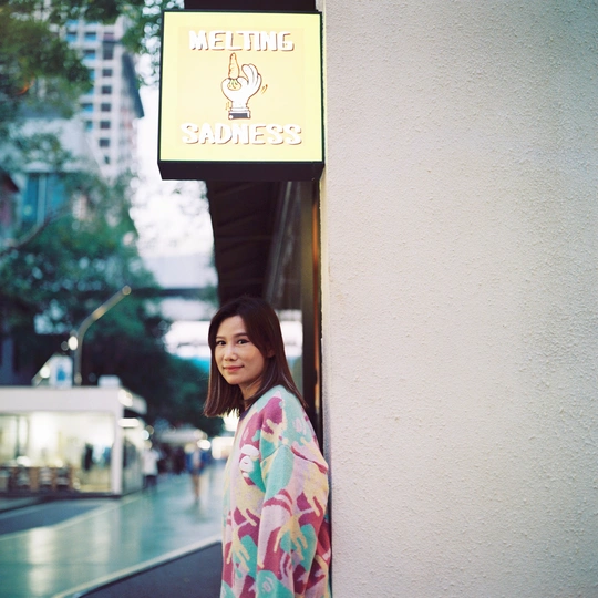 一位穿着和服的年轻女子靠在街上的一堵墙边