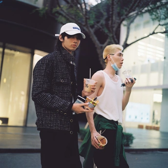 一位年轻男子和女子站在人行道上 各拿着一杯饮料。