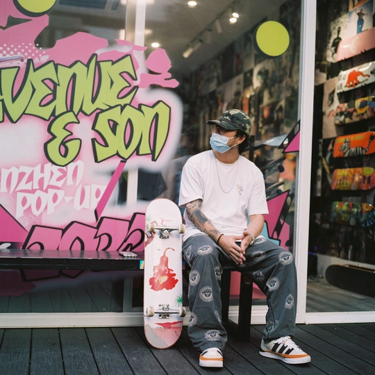 一个戴面罩的年轻人坐在一家有涂鸦墙的商店前的长椅上