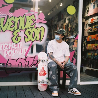 一个戴面罩的年轻人坐在一家有涂鸦墙的商店前的长椅上