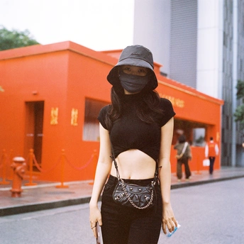 一位戴黑色帽子和面罩的女人正在街上走