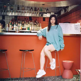 一位坐在酒吧前蓝色墙壁前的长凳上的女士