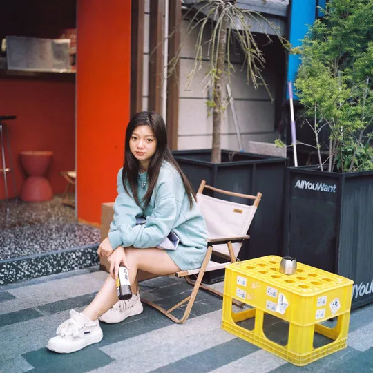 一位年轻女子坐在黄色桌椅前的地板上