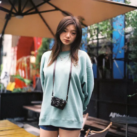 一个穿蓝色毛衣和过膝靴的女孩站在一把伞下